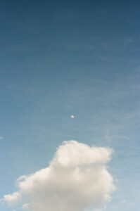 Film photo of an empty sky with only the moon and one cloud visible