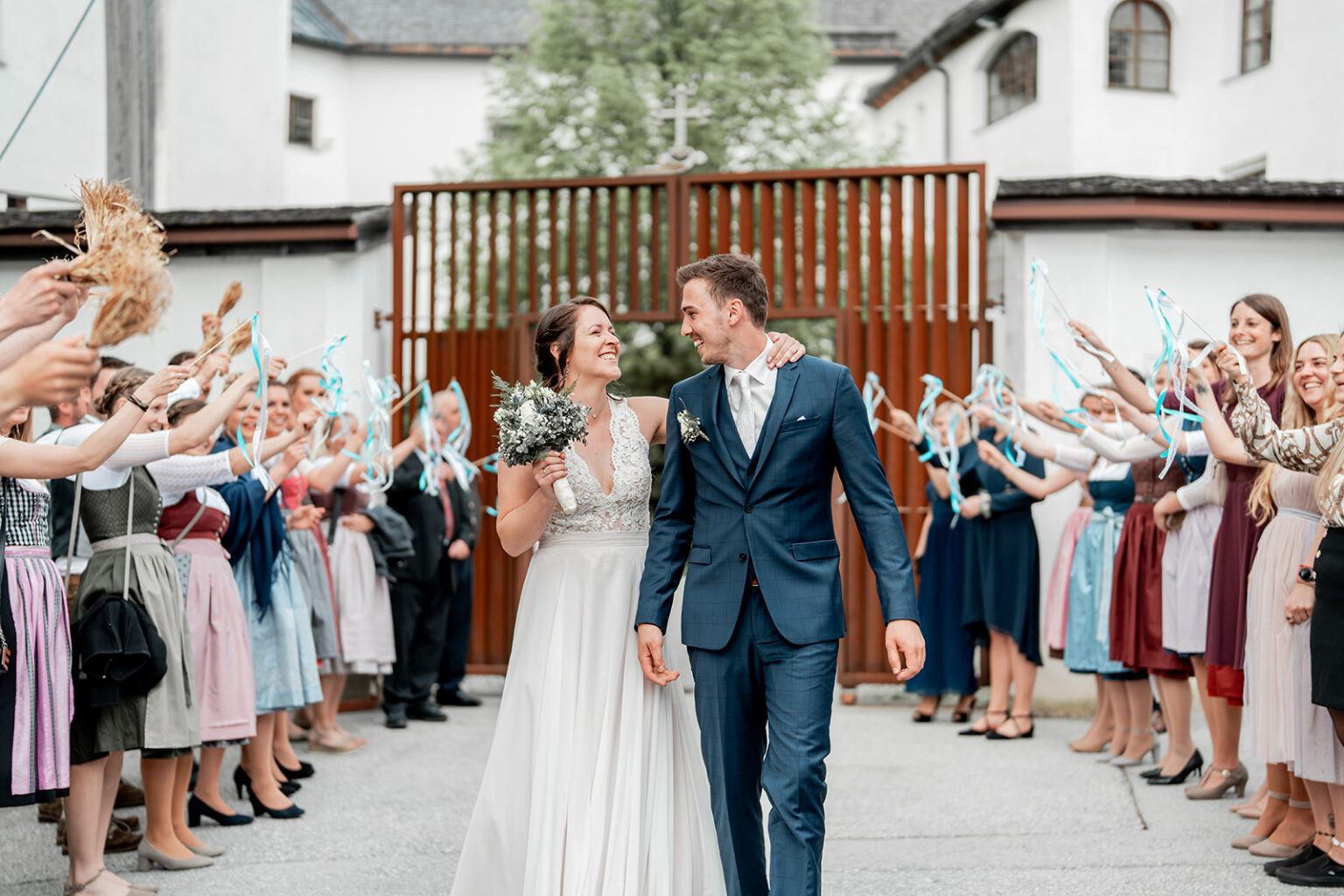 Couple walking past cheering guests after their ceremony while smiling at each other