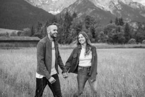 Young couple walking through tall grass with the Wilder Kaiser mountains in the background