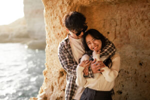 Man embracing his girlfriend from behind while she laughs at the camera