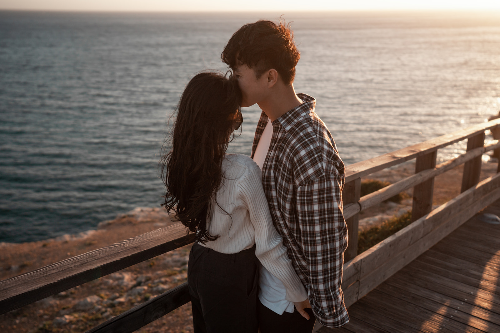 Man kissing his fiancée on the forehead overlooking the Atlantic coast of the Algarve