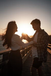Couple playfully moving their hands together at sunset while laughing