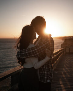 Couple embracing at sunset by the ocean with their heads leaning together
