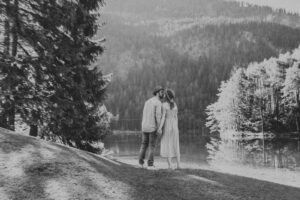 Black-and-white photo of a couple by the lakeshore just before a kiss