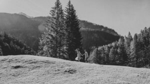 Blurry grainy black-and-white photo of a couple running across a meadow in morning light