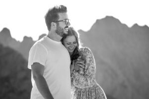 Black-and-white photo of a couple walking in a half embrace in the mountains