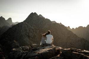 Evening atmosphere in the mountains with a couple cuddling on a rock