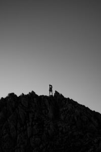 Silhouette photo of a couple on a mountain peak with their heads leaning together