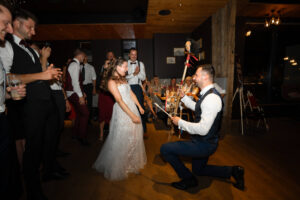 The groom kneels on the dance floor and performs for his bride