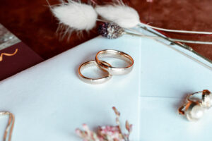 Close-up of wedding rings on an invitation envelope with pampas grass