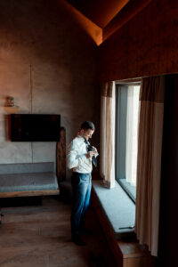 Distant shot of the groom getting ready by a window
