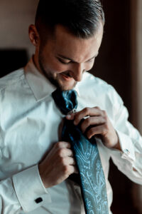 Close-up of the groom adjusting his tie