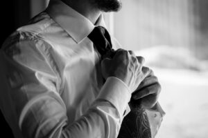 Black-and-white photo of the groom adjusting his tie