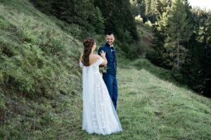 The bride taps the groom on the shoulder as he turns toward her with a smile
