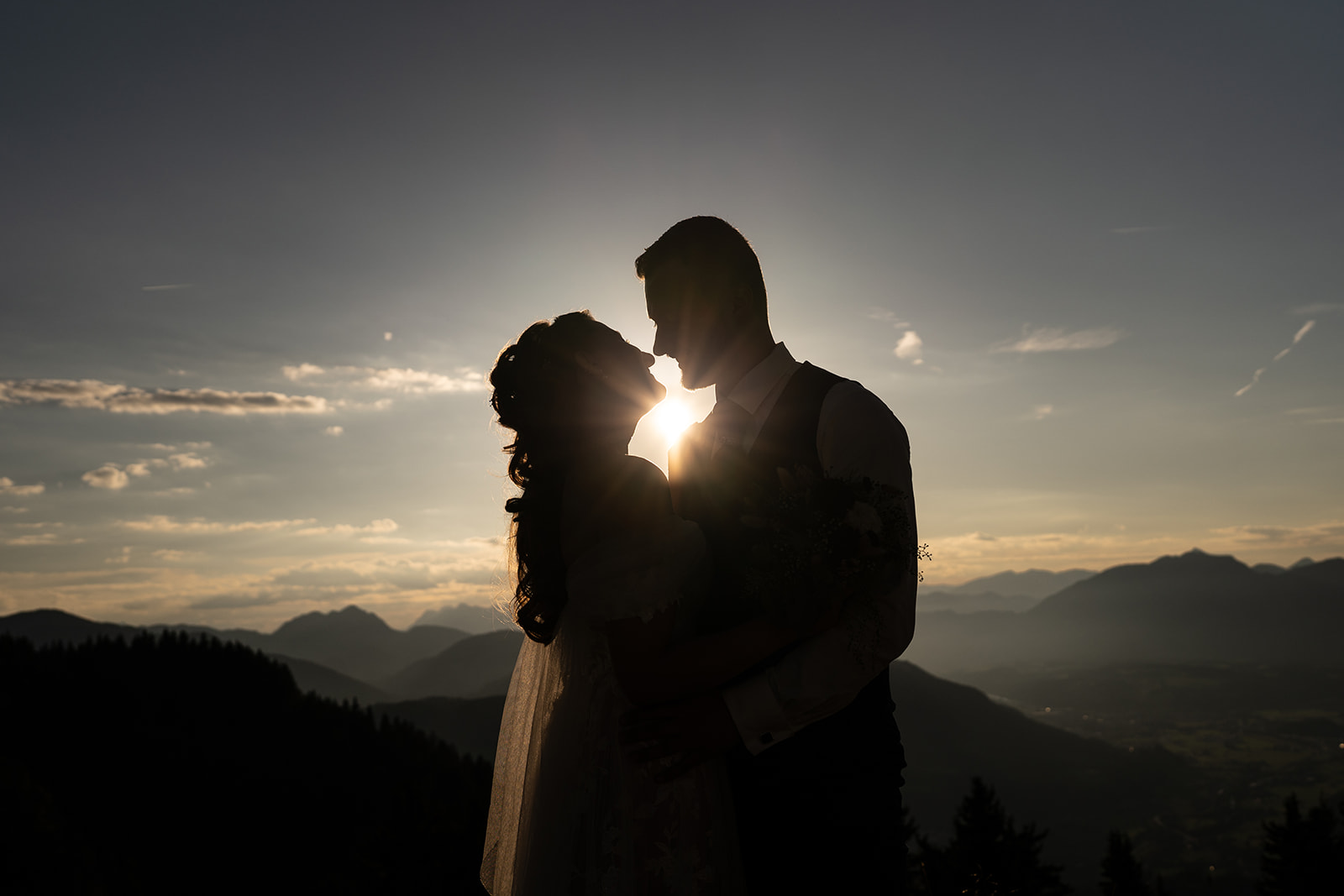 Silhouette photo of a wedding couple at sunset with mountains in the background