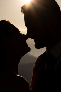 Silhouette of the wedding couple touching noses in backlight