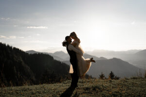 The groom lifts his bride as they lean their heads together