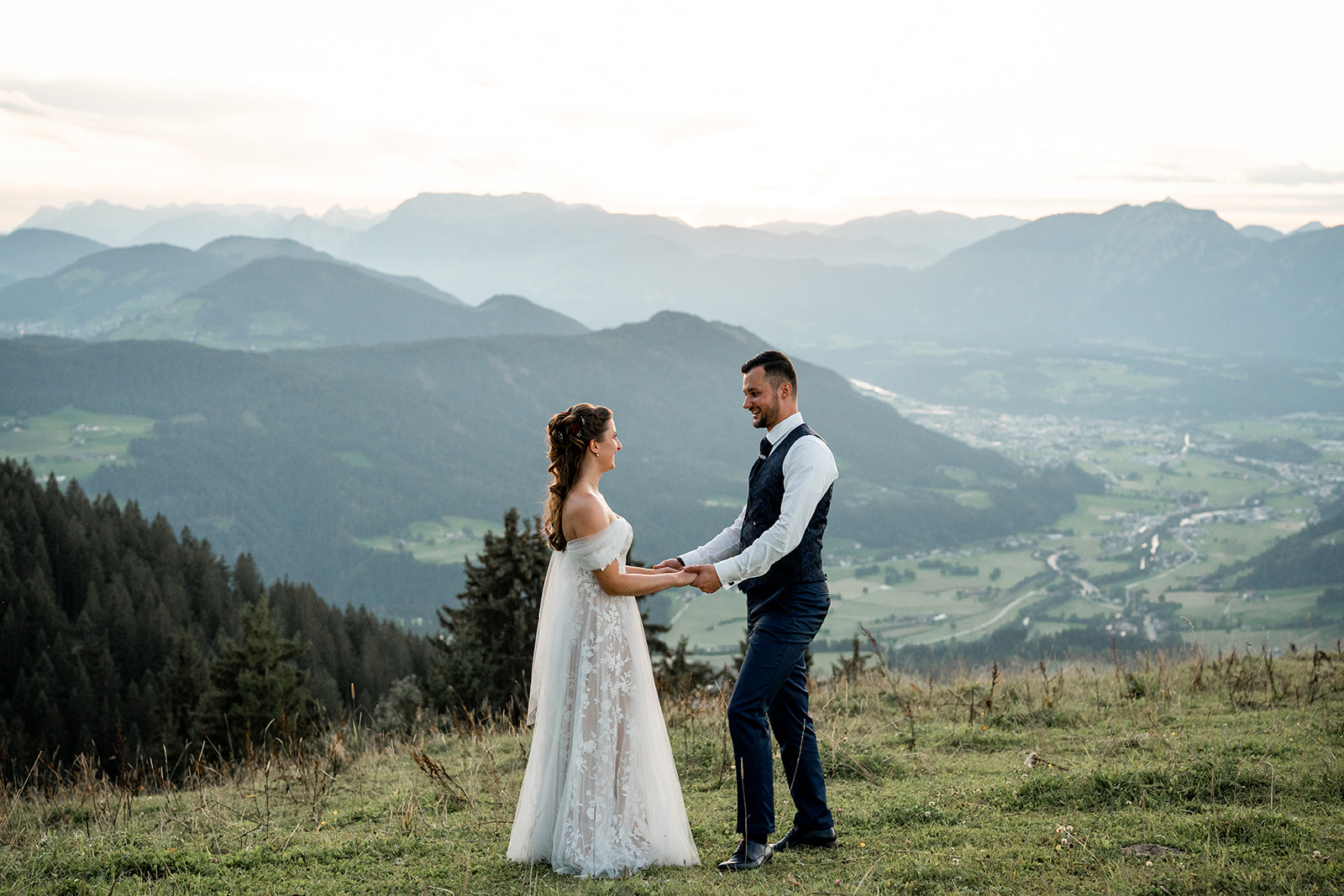 Wedding couple holding hands at sunset in the mountains while looking at each other