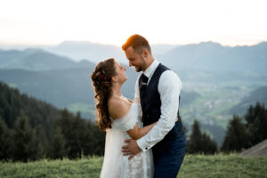 Bride and groom embrace at sunset as the sun shines between them