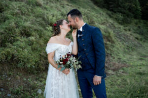 The wedding couple kisses as the bride holds the groom’s chin