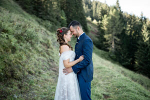 The wedding couple stands forehead to forehead in a field, enjoying the first moments after their first look