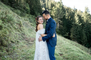 Bride and groom embrace while the bride smiles toward the camera