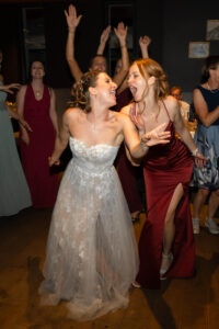 Bride and bridesmaid singing together on the dance floor