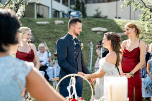 Bride and groom stand hand in hand before their guests after the ring exchange