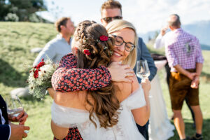 A friend warmly hugs the bride while smiling