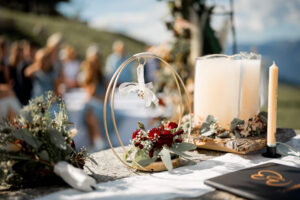 Close-up of wedding rings attached to a ribbon on a flower-decorated metal hoop
