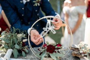 Close-up of the groom’s hands removing the rings from the ribbon