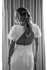 The bride photographed from behind in front of a curtain, looking down to the left