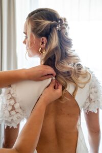 The wedding dress being fastened from the back
