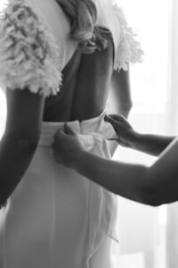 Black and white photo of a bow on the wedding dress being adjusted