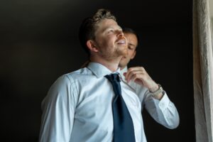 The best man adjusts the groom's collar