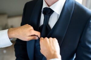 Close-up of hands adjusting the groom's tie