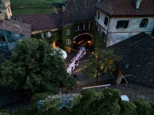 Side drone view of the illuminated courtyard of Castle Rametz with a long wedding dinner table