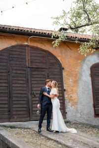 Bride and groom kissing in front of a historic gate with terracotta walls in the courtyard
