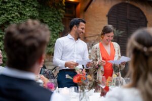 Best man smiling toward the maid of honor while giving their speech together