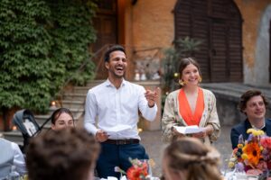 Maid of honor and best man laughing warmly toward the couple while pointing into the distance