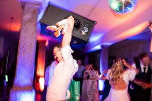 Creative motion blur photo of a party guest holding a boombox and women's shoes above his head