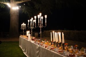 Side view of the wedding dessert table with cakes, candles, and string lights