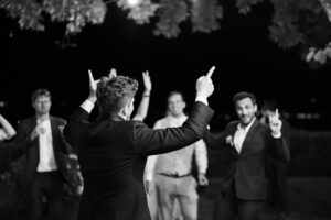 Black and white photo of wedding guests dancing with their hands raised