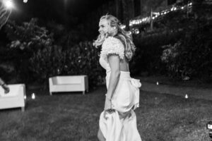 Black and white photo of a bride dancing joyfully on the field