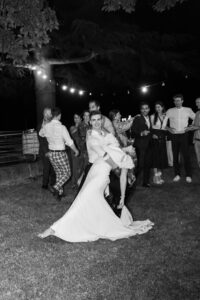 Black and white photo of a young man dancing with the bride and dipping her backward