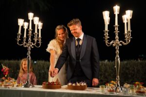 Bride and groom cutting their wedding cake together while laughing joyfully
