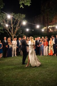 First dance of a bride and groom on an open field beneath string lights