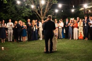 Bride standing behind her groom and gently placing her hand on his head while dancing