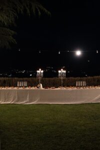 Wedding dessert table with a variety of cakes beneath the evening sky and moon