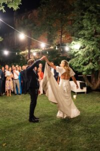 Groom twirling his bride during their first dance as her dress flows gracefully